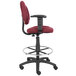 A Boss burgundy drafting stool with footring and adjustable arms on a black base.
