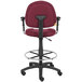 A Boss burgundy drafting stool with a black base and adjustable arms.