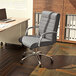 A Boss Modern Executive Gray Ribbed CaressoftPlus conference chair in front of a desk with a laptop on it.