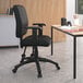 A black Boss office chair with adjustable arms at a desk with a laptop.
