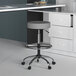 A Boss gray vinyl drafting stool with a round seat and wheels.