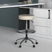 A beige Boss Caressoft vinyl stool with a round base under a desk.