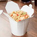 A white SmartServ paper take-out container filled with noodles and vegetables.