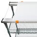 A white cutting board with orange handles on a metal shelf.