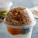 A bowl of yogurt and granola with a clear plastic dome lid on it.