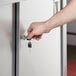A hand opening a Regency stainless steel table cabinet door with a key.
