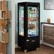 An Avantco black glass door merchandising refrigerator filled with drinks.