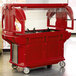 A red food cart with a clear lid.