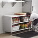 A man in a white shirt and black apron putting food on a Regency stainless steel shelf.