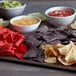A table with bowls of salsa and guacamole and a plate of Mission 4-cut tortilla chips.