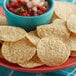 A plate of Mission white round corn tortilla chips with a bowl of salsa.