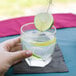 A hand holding a Libbey Chivalry Rocks Glass of water with a slice of lime on it.