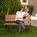 A woman sitting on a Lifetime brown convertible bench reading a book.