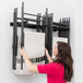 A woman using the Lifetime Wall-Mounted Folding Chair Rack to hold chairs.