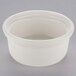 A white Tuxton eggshell china casserole dish with a lid on a gray surface.