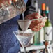A person using the Arcoroc stainless steel fine mesh strainer to pour a drink into a martini glass.