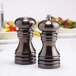 A Chef Specialties burnished copper pepper mill and salt shaker set on a table.