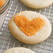 Heart shaped cookies with an orange sugary coating.