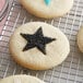 Star shaped cookies on a cooling rack decorated with black sanding sugar.