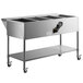 A stainless steel ServIt food cart with a steam table and undershelf holding four pans.