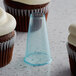 A cupcake with frosting and a plastic cup on a counter with an Ateco plain piped design.