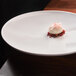 A Front of the House white porcelain plate with a small white dessert on it.