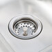 A close-up of the drain on a stainless steel Advance Tabco hand sink.