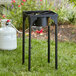 A black square Backyard Pro outdoor stove with adjustable legs and a white gas cylinder sitting on the grass.