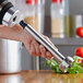 A hand holding a silver Galaxy 9" immersion blender shaft.
