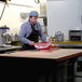 A man cutting meat on a red Vollrath cutting board on a table.