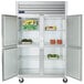 A Traulsen G Series reach-in refrigerator with two doors full of food on shelves.