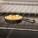 An American Metalcraft pre-seasoned mini cast iron skillet filled with macaroni and cheese on a table.