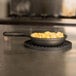 An American Metalcraft pre-seasoned mini cast iron skillet filled with macaroni and cheese on a stove.