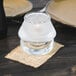 A Sterno clear glass candle holder on a table.