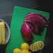 A Vollrath green cutting board with corn, red cabbage, and yellow corn on it.