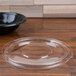 A clear plastic bowl with a clear plastic lid on a wood surface.