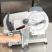 A person using a Centerline by Hobart manual meat slicer to cut food.