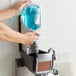 A person using a Rubbermaid Lumecel automatic soap dispenser to refill it with soap.