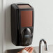 A person's hand washing with a Rubbermaid Lumecel soap dispenser.