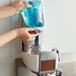 A person using a Rubbermaid Lumecel automatic soap dispenser.