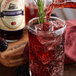 A glass of Reading Soda Works Blackberry Cream soda with ice on a table with a bottle of the soda.