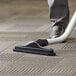 A person's foot using a Lavex carpet tool to vacuum a carpet.