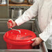 A chef using a red Chef Master salad spinner with a handle.