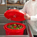 A chef using a Chef Master red plastic salad spinner to dry lettuce.