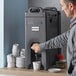 A man pouring coffee into a black insulated beverage dispenser.