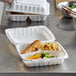 A white Dart ProPlanet hinged lid takeout container with three compartments holding food.