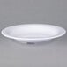 A white Carlisle melamine bowl with a rim on a gray surface.
