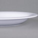A close-up of a white Carlisle melamine bowl with a rim.