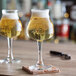 Two Libbey tall stemmed beer glasses on a wooden table.