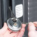 A person using a key to open a lock on a Cambro food pan carrier with a security package.